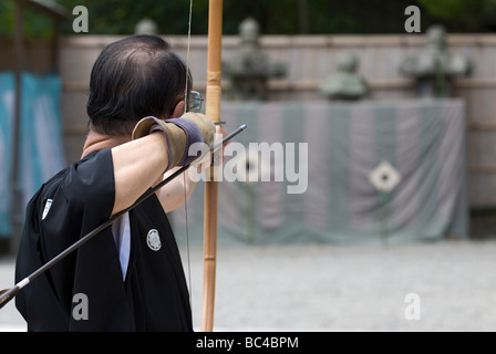 L'homme japonais exécutant l'art du tir à l'arc, ou kyudo (弓道 ?), se concentre avant de relâcher la flèche lors d'une démonstration d'arts martiaux à Kyoto, au Japon. Banque D'Images