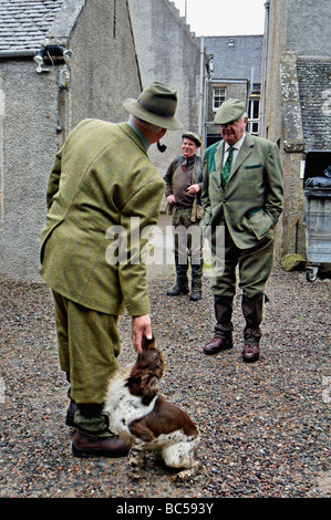 Ghillie flatter son chien tout en parlant aux clients avant conduit le lagopède des saules a tirer dans les Highlands d'Ecosse Banque D'Images