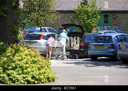 Femme et sa fille laoding leur voiture avec des plantes après leur achat dans un centre de jardinage Banque D'Images