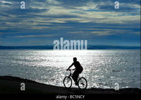 PENZANCE, CORNWALL, Royaume-Uni - 09 JUIN 2009 : silhouette de cycliste contre le soleil sur Mounts Bay Banque D'Images