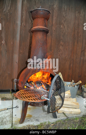 Le bois brûle dans un chiminea le jardin. Banque D'Images