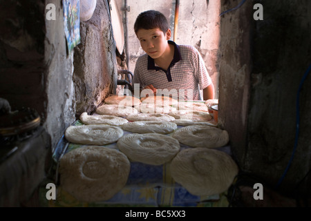 Une visite d'une boulangerie locale en Ouzbékistan, l'Asie centrale : Jeune garçon et pain traditionnel (Naan, Nan, Non, Nun) dans un four. Banque D'Images