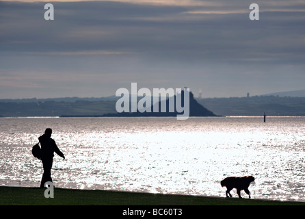 PENZANCE, CORNWALL, Royaume-Uni - 09 JUIN 2009 : silhouette de Dog Walker contre le soleil sur Mounts Bay Banque D'Images