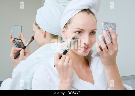 Jeune femme à l'aide de make-up pinceau, portrait Banque D'Images