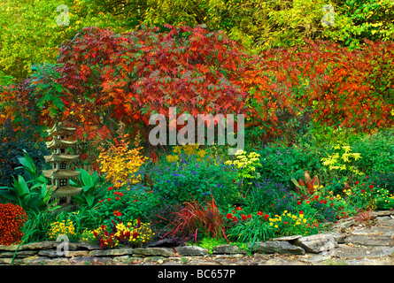 Pagode japonaise ornementales statue placée dans jardin de plantes en fleurs de couleur vive dans un jardin rouge et jaune, Midwest USA Banque D'Images