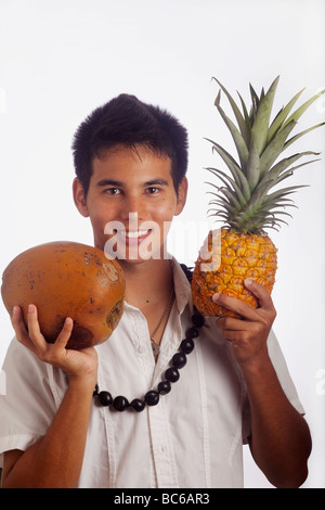 Un homme portant un Hawaiian kukui nut lei est titulaire d'un ananas et d'une noix de coco Banque D'Images
