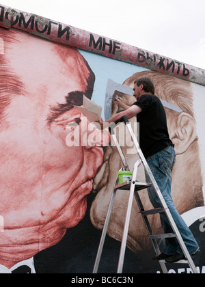 Artiste russe Dimitry Vrubel repeindre sa fameuse fresque originale de Brejnev embrassant Honecker juin sur le mur de Berlin Banque D'Images