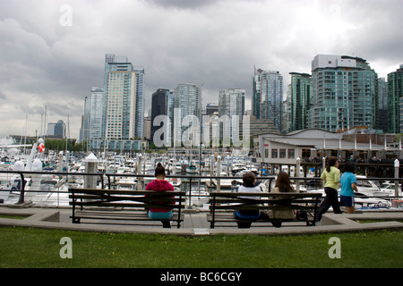 Condos haut de gamme à Coal Harbour, un centre-ville connu pour sa marina, sa vue sur la montagne et ses restaurants. Au premier plan, les gens se détendent sur des bancs Banque D'Images