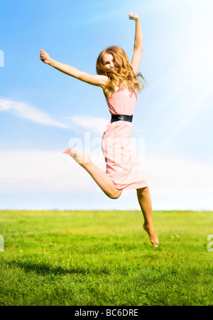 Happy girl jumping sur fond d'été à l'extérieur Banque D'Images