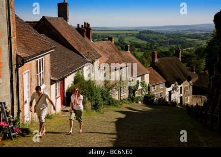 Un couple marche vers le haut de la célèbre rue pavée, sur la colline d'or à Shaftesbury Banque D'Images