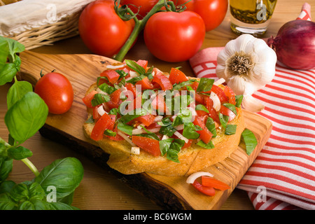 Pain bruschetta italienne servi sur planche en bois d'olive, décoré avec divers ingrédients Banque D'Images