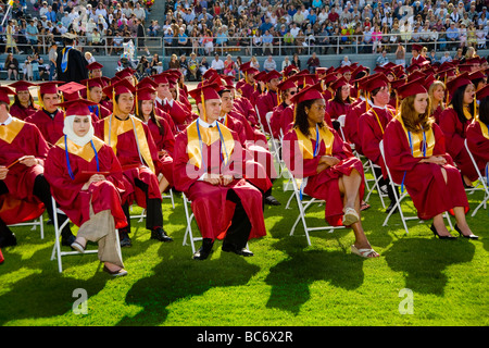 Porter des robes et chapeaux de seniors de lycée participer à des diplômes à Huntington Beach CA Banque D'Images