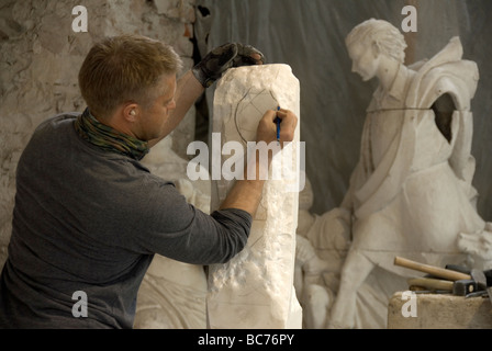 Un sculpteur s'appuie sur un bloc de pierre qu'il sculpte dans la sculpture Nicoli Studios Carrara Banque D'Images