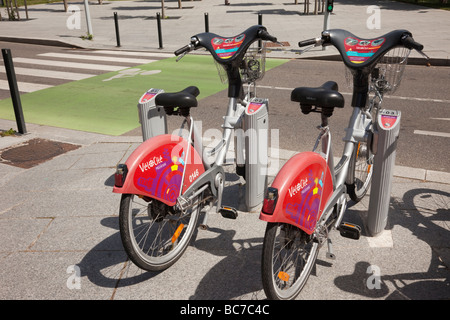 Mulhouse Alsace France Europe Velocity vélos électriques à louer par les piétons et les cyclistes au franchissement routier ville Banque D'Images