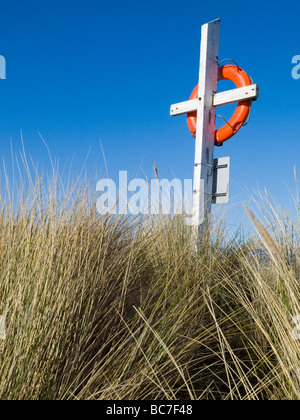 Gros plan d'une bouée de couleur orange vif dans les dunes sur la plage à Largs, sur la magnifique côte de Northumberland England UK Banque D'Images