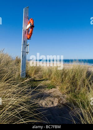 Gros plan d'une bouée de couleur orange vif dans les dunes sur la plage à Largs, sur la magnifique côte de Northumberland England UK Banque D'Images