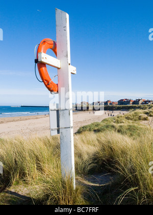 Gros plan d'une bouée de couleur orange vif dans les dunes sur la plage à Largs, sur la magnifique côte de Northumberland England UK Banque D'Images