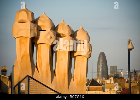 Cheminées au coucher du soleil et ciel bleu au toit de la Casa Milà de Gaudí sur les toits de la ville y compris la tour Agbar en arrière-plan. Banque D'Images