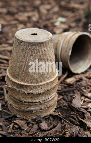 Re utilisé des pots de semences compostables brun écorce empilés sur des gravillons dans un jardin biologique Banque D'Images