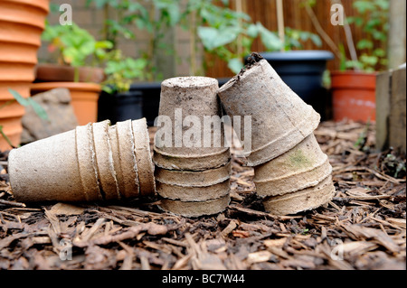 Re utilisé des pots de semences compostables brun écorce empilés sur des gravillons dans un jardin biologique Banque D'Images