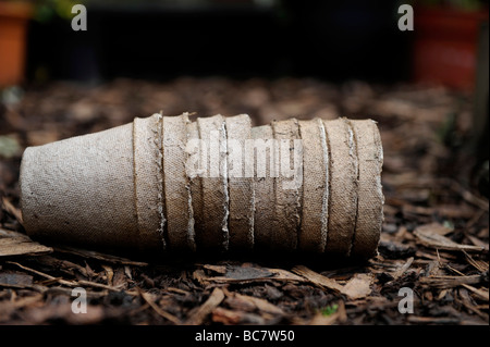 Re utilisé des pots de graines brun compostables empilés sur des débris d'écorce dans un jardin biologique Banque D'Images