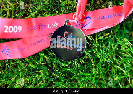 Course à la médaille de la vie lying on grass Banque D'Images