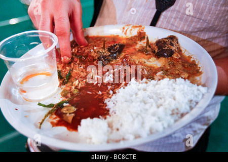 Un occidental mange un repas indien directement avec ses mains dans la façon traditionnelle d'Inde du sud. Banque D'Images