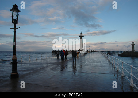 Les gens prennent une promenade hivernale le long de la jetée de Whitby Banque D'Images
