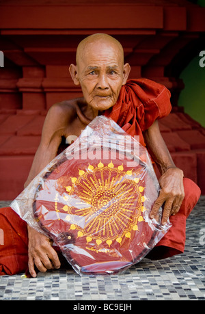 Ancien moine bouddhiste avec un ventilateur peint dans ses mains dans la pagode Shwedagon à Yangon, Myanmar Banque D'Images