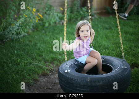 Portrait de jeune fille sur balançoire pneu in backyard Banque D'Images