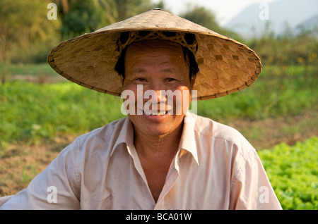 Gros plan portrait d'un fermier souriant et heureux portant un grand chapeau de paille dans son jardin de côté de rivière à Luang Prabang Laos Banque D'Images