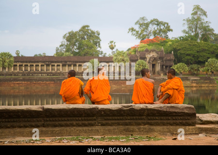 Quatre moines bouddhistes khmers reposant sur mur de pierre de douves extérieures à Phnom Penh - cambodge Banque D'Images