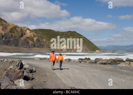 Deux randonneurs sur les Roches Rouges promenade côtière, Owhiro Bay, près de Wellington, Île du Nord, Nouvelle-Zélande Banque D'Images