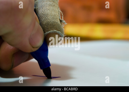 Un gros plan d'un homme part avec un plâtre à l'écriture avec un stylo bleu. Banque D'Images