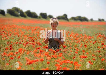 Blonde femme debout dans un champ de coquelicots juste au nord de Brighton à Brighton and Hove dans l'East Sussex Banque D'Images