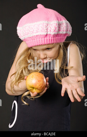 Drôle de surprise petite fille avec apple sur fond noir Banque D'Images