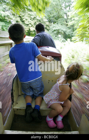 Les jeunes passagers sur un train de chemin de fer miniature dans le parc Banque D'Images