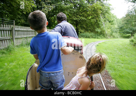 Les jeunes passagers sur un train de chemin de fer miniature dans le parc Banque D'Images