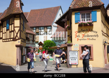 Les gens chargés de boîtes de vin acheté à partir de la Cave des Producteurs de vin shop dans village médiéval sur la route des vins d'Eguisheim Alsace France Banque D'Images