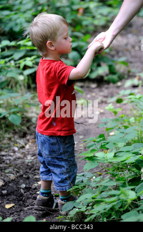 Petit enfant garçon blond de manger des myrtilles avec la mère dans la forêt Banque D'Images