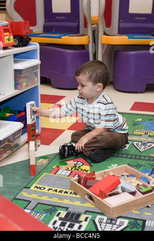 Préscolaire 4 ans garçon assis sur le sol les blocs d'empilage Banque D'Images