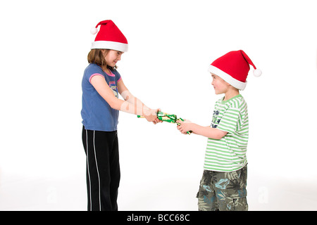 Les jeunes enfants tirant une Christmas Cracker Banque D'Images