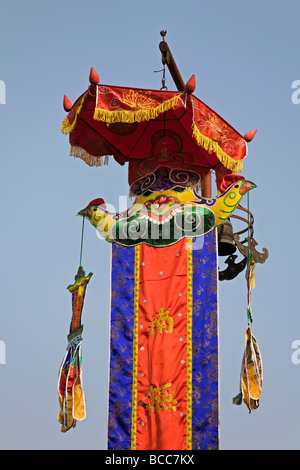 Pôle décorées avec parapluie coqs et de bannière érigée en dehors du temple à côté de la Pagode à un pilier à Hanoi Banque D'Images