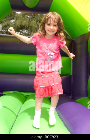 Jeune fille s'amusant sur un château gonflable en été, pour un fayre dans Blackmoor près de Bordon, Hampshire, Royaume-Uni. Banque D'Images