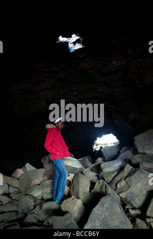 Teenage Girl standing à l'intérieur d'une grotte. Surtshellir, grotte de lave Hallmundarhraun, à l'ouest de l'Islande. Banque D'Images