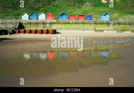 Cabines de plage sur la digue à Overstrand, Norfolk, Royaume-Uni, avec des réflexions sur la plage. Banque D'Images