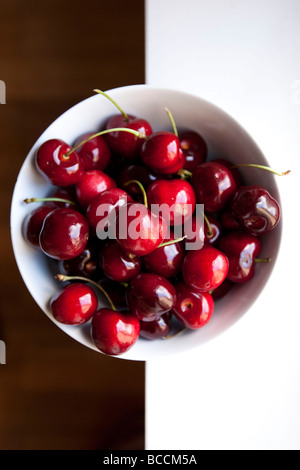 Poignée de cerise rouge avec des tiges dans une cuvette ronde blanche Banque D'Images