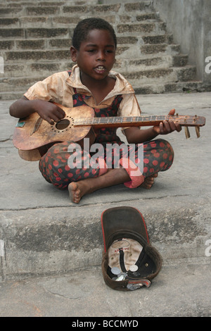 Garçon malgache chantant et jouant de la guitare sur une rue d'Antananarivo, Madagascar Banque D'Images