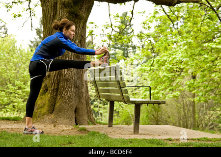 Une femme s'étire avant de partir sur une course dans un parc de Portland, Oregon. Banque D'Images