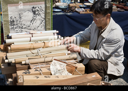 Un homme regarde à travers une collection de rouleaux de kakejiku antiques à un marché aux puces en plein air à Kyoto au Japon Banque D'Images